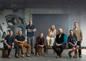 Group of business leaders and Kinesians posed together in an engineering warehouse