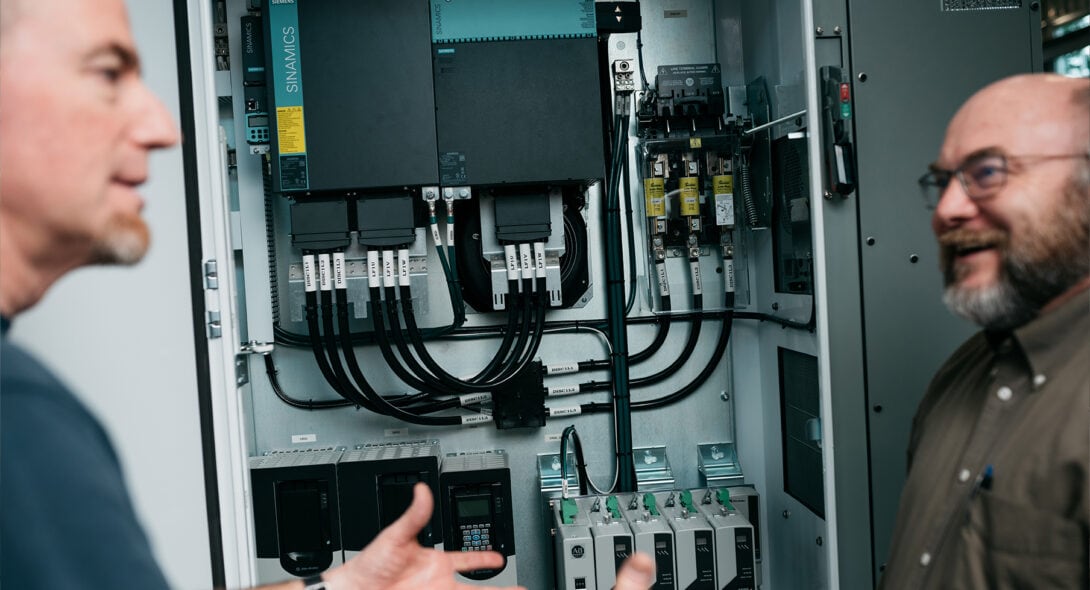 Team members discussing an open electrical panel