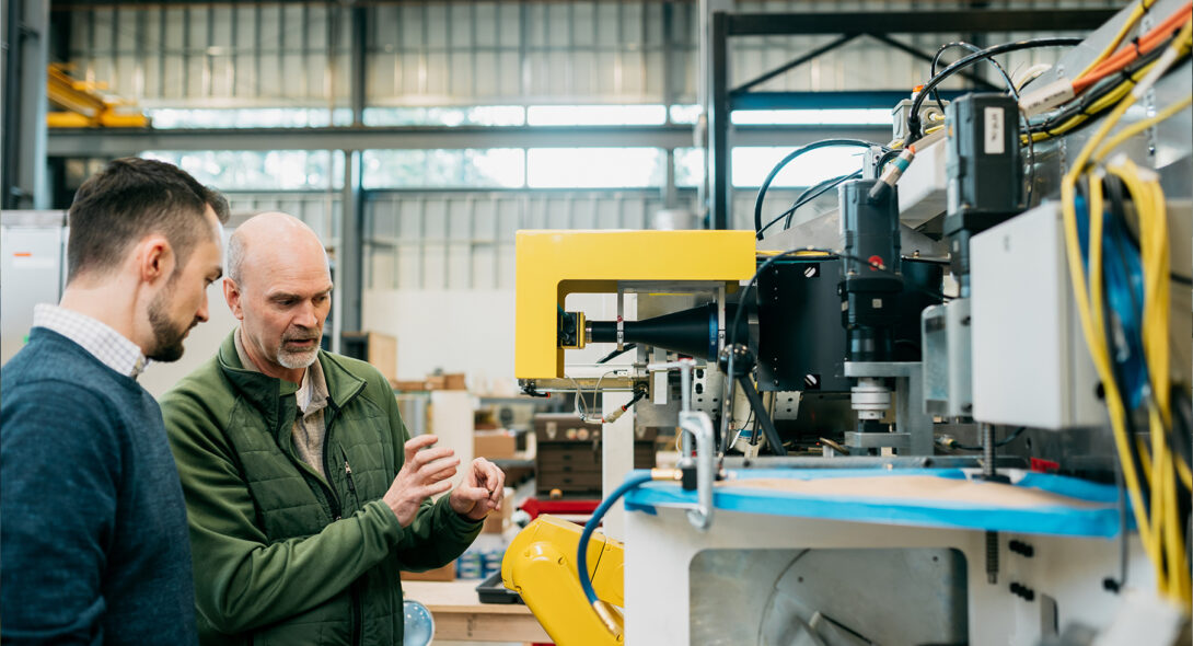 Team members discussing machine on shop floor